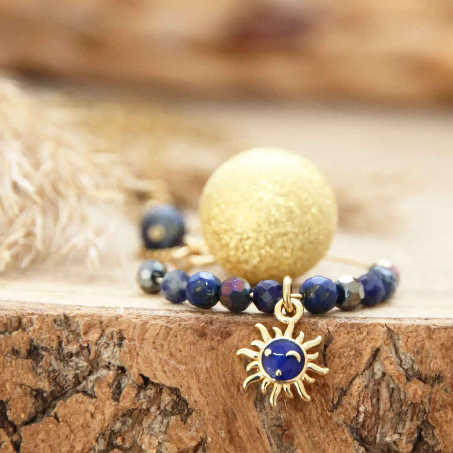 Gros plan sur le bola de grossesse doré et sa breloque soleil bleu en gold filled.